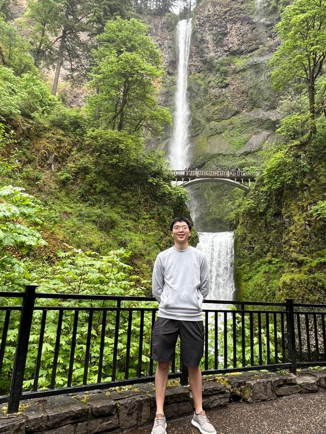 Shao in front of Multnomah Falls, the bridge and upper falls rising behind him.