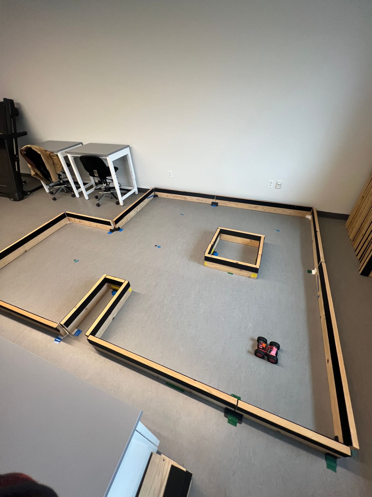 The taped-out test arena: a wooden-walled course on a lab floor with the robot parked inside.