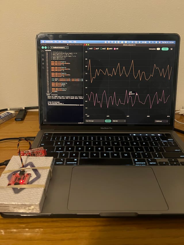 A laptop plotting two live sensor traces beside the robot's microcontroller board on a breadboard.